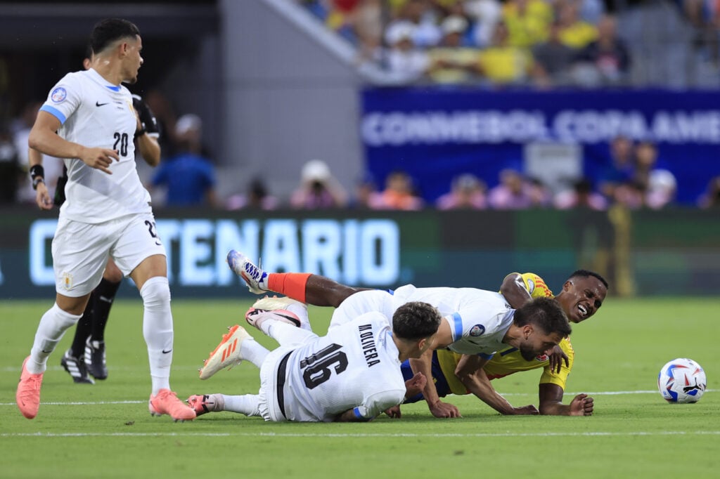 Jhon Arias of Colombia falls down with Mathias Olivera and Rodrigo Bentancur of Uruguay during the CONMEBOL Copa America 2024 semifinal match betwe...